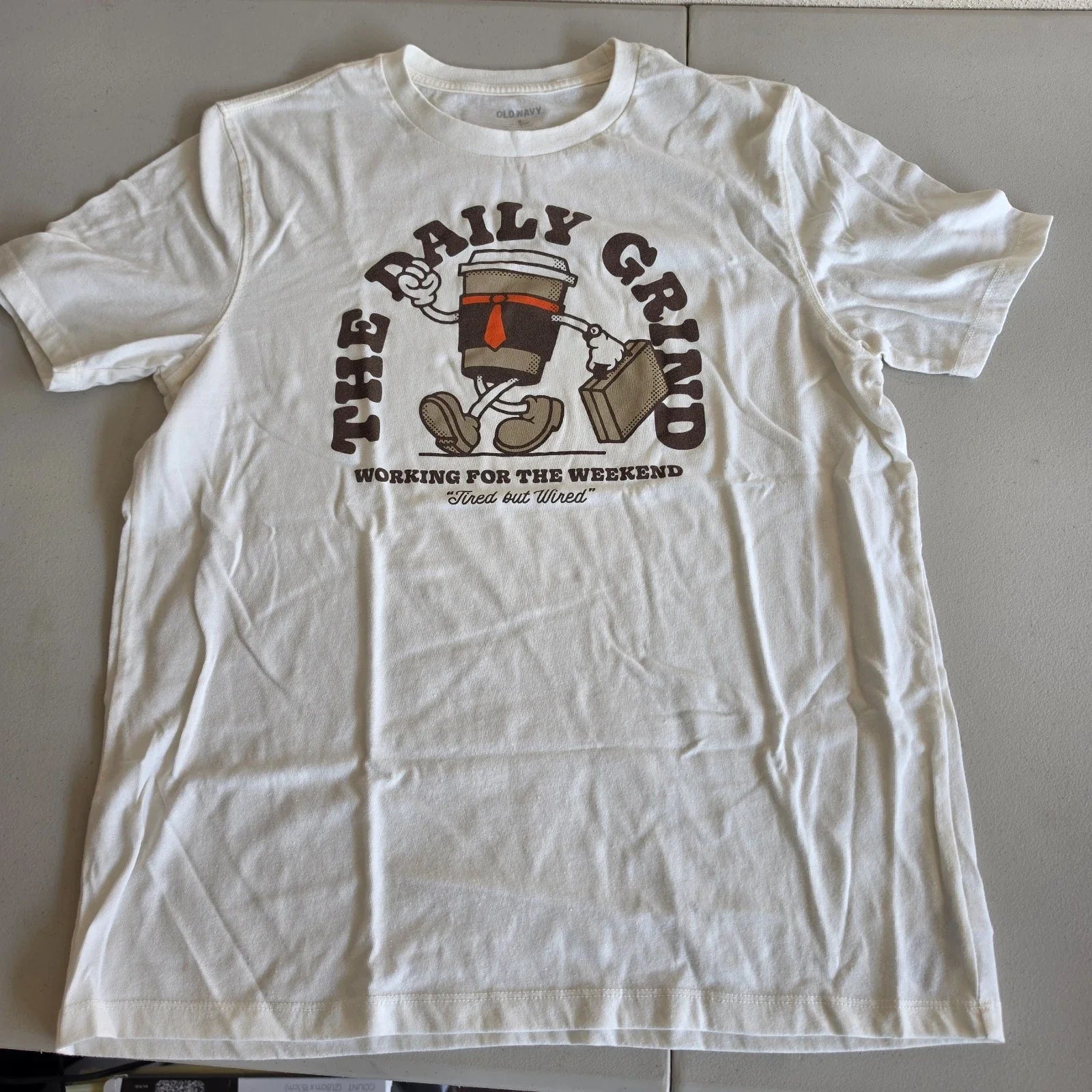 The Daily Grind Shirt by Old Navy Coffee Cup Graphic Cream Color Adult Size M Unisex T-shirt, Sweatshirt, Hoodie, Long Sleeve Tee - T-Shirt, Sweatshirt, Hoodie